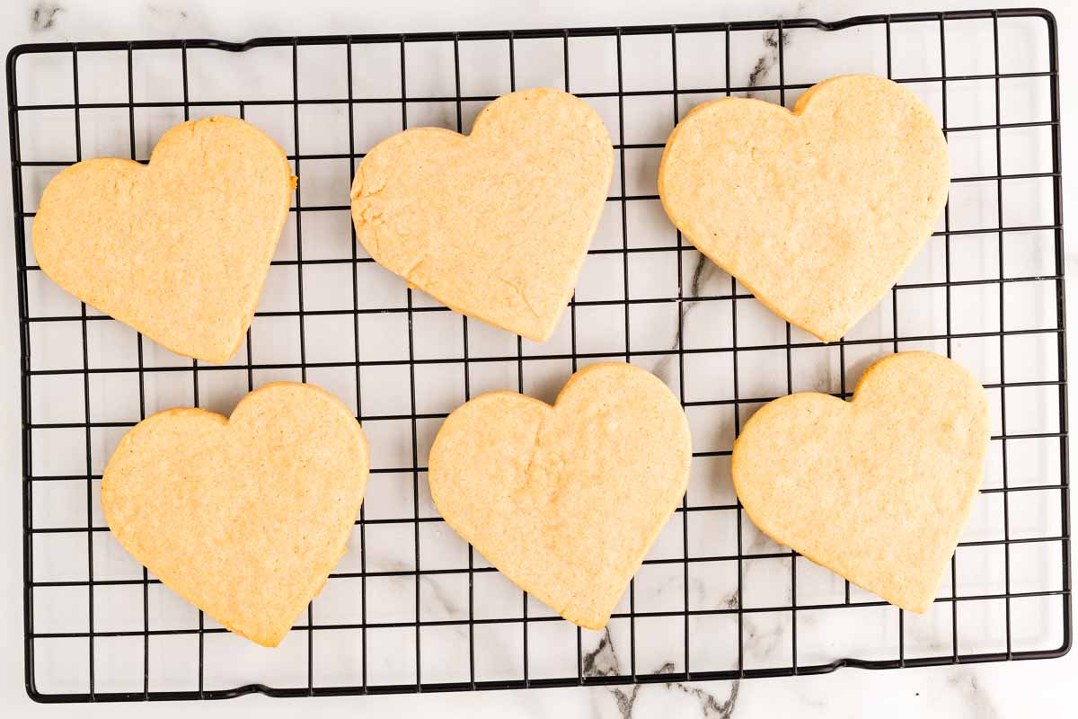 Heart shaped sugar cookies cooling on a wire rack.
