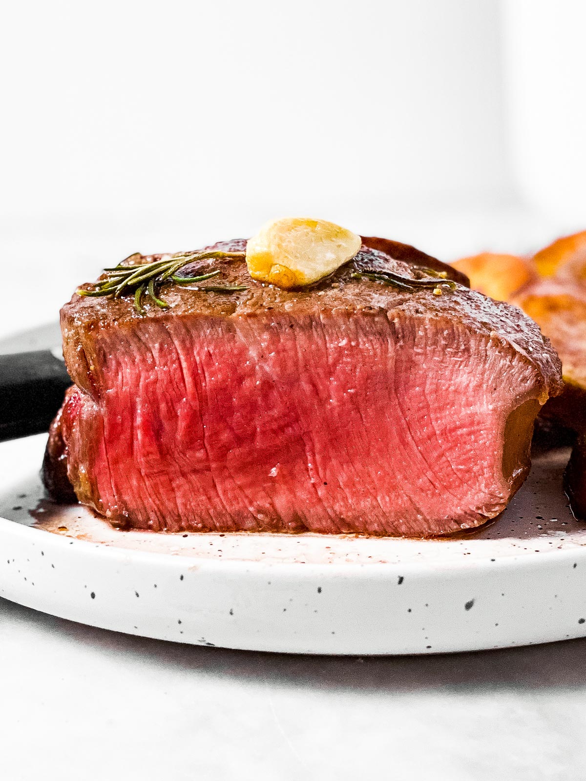 frontal view of sliced filet mignon on white plate