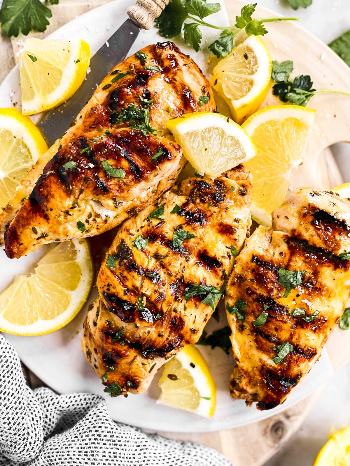 overhead view of three grilled chicken breasts seasoned with Greek marinade