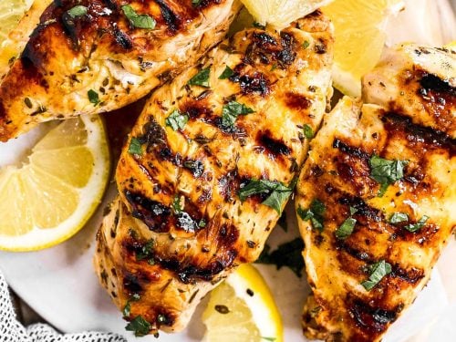 overhead view of three grilled chicken breasts seasoned with Greek marinade