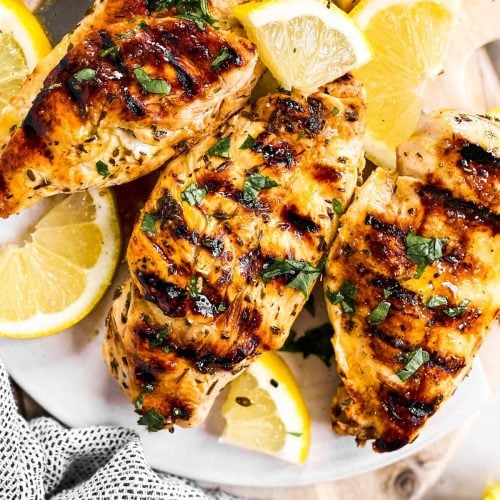 overhead view of three grilled chicken breasts seasoned with Greek marinade
