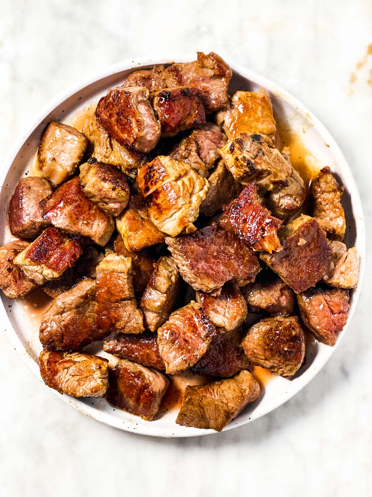 browned steak bites on white plate