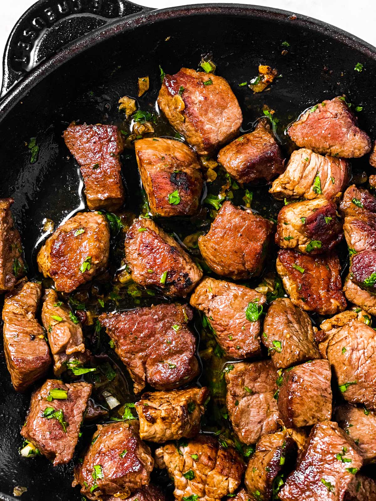 overhead view of garlic butter steak bites in cast iron skillet