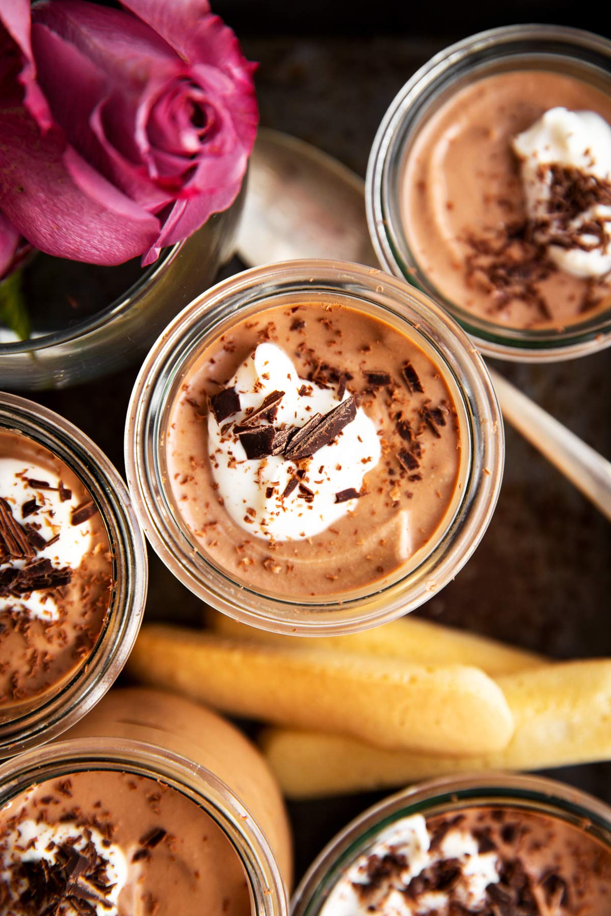 overhead view of tiramisu chocolate mousse in small glass jar on black metal tray