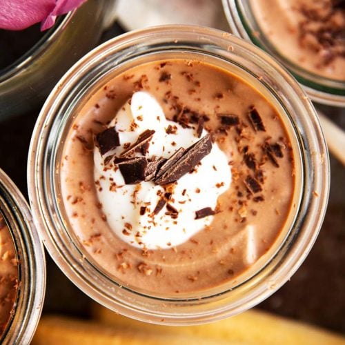 overhead view of tiramisu chocolate mousse in small glass jar on black metal tray