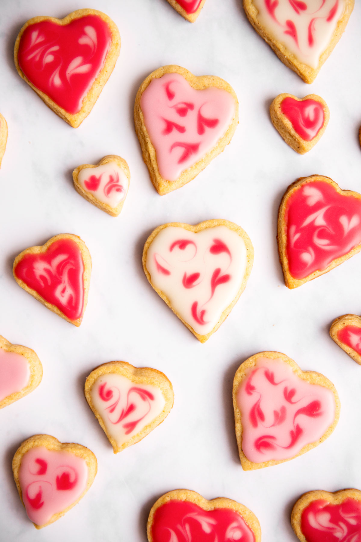 several heart shaped, iced sugar cookies on marble surface