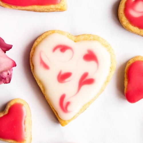 overhead close up view of valentine's day sugar cookie on marble surface with pink roses