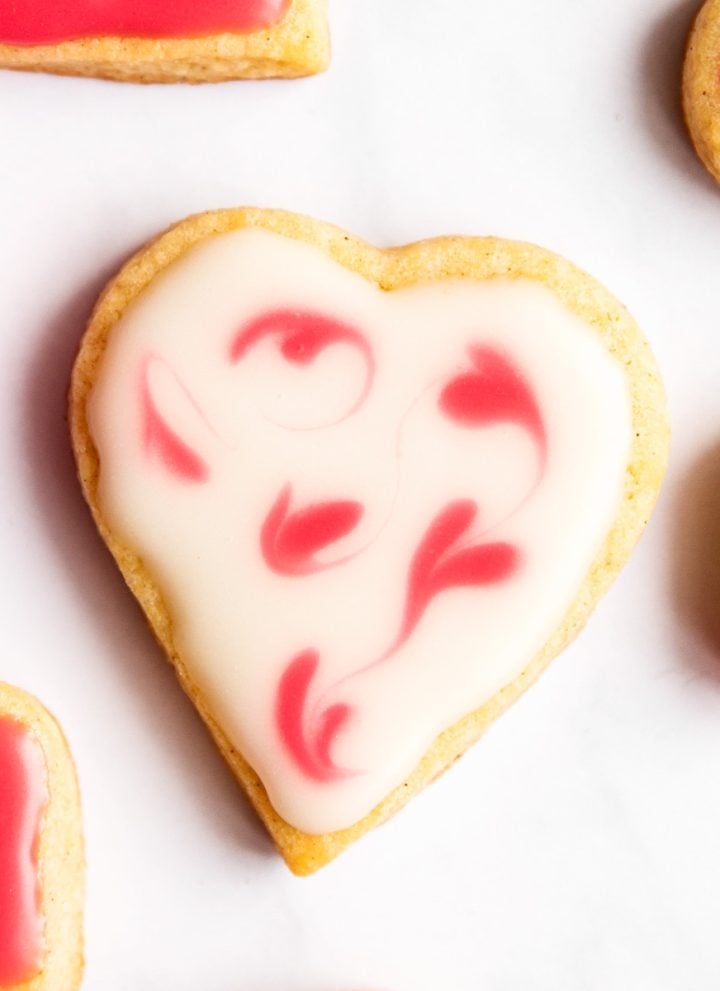 overhead close up view of valentine's day sugar cookie on marble surface with pink roses
