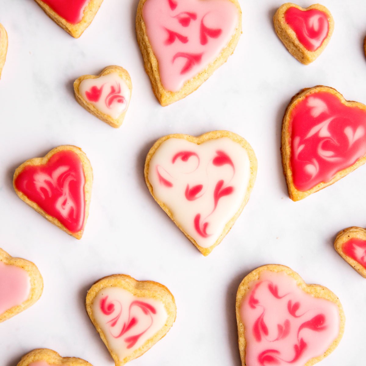 overhead view of several decorated valentine's day sugar cookies on marble surface