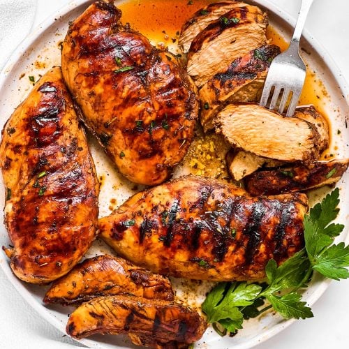 overhead view of grilled chicken breast in balsamic marinade on white plate