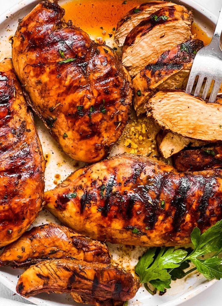 overhead view of grilled chicken breast in balsamic marinade on white plate
