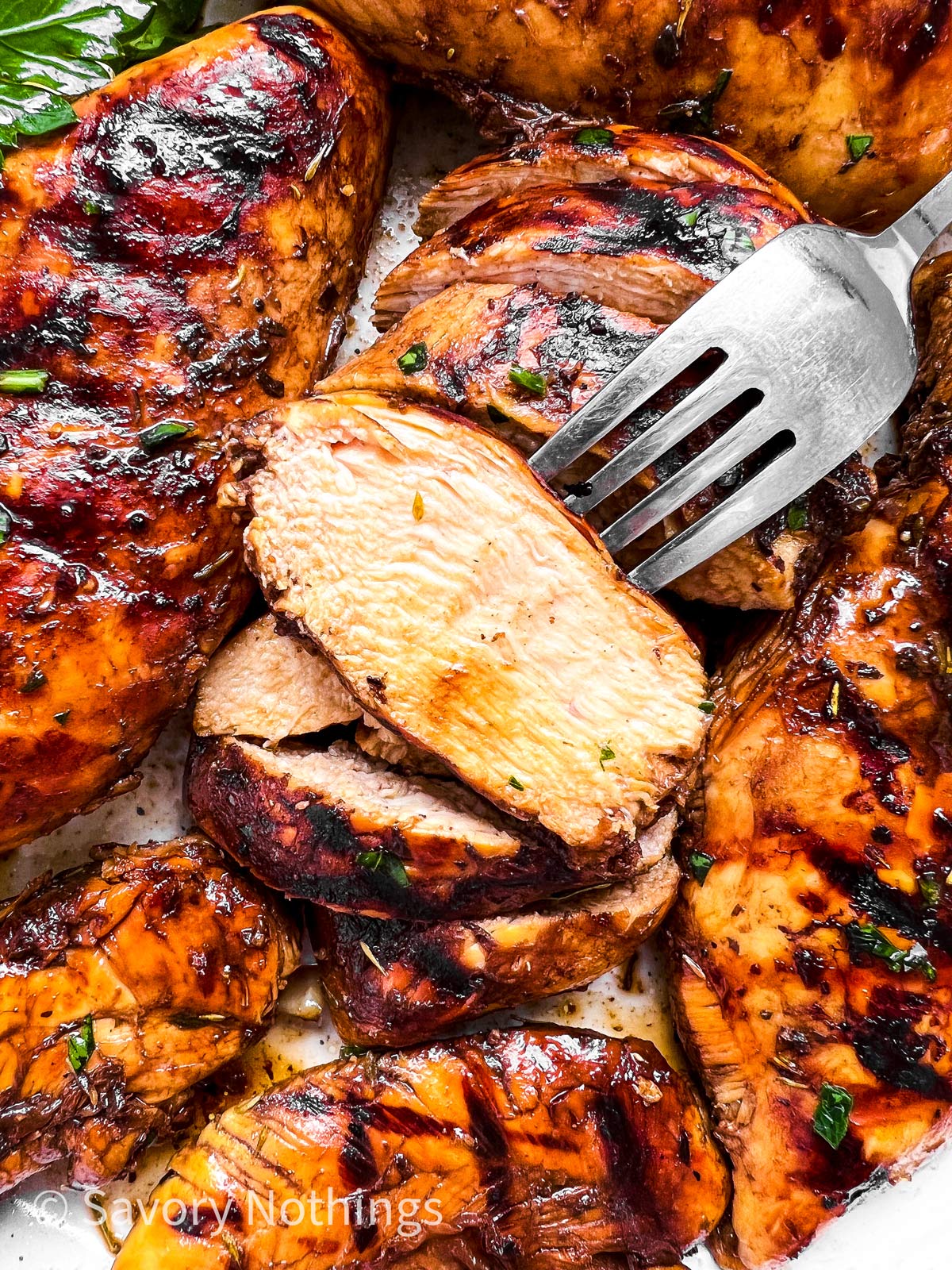 overhead view of sliced balsamic grilled chicken breast with fork stuck in one piece