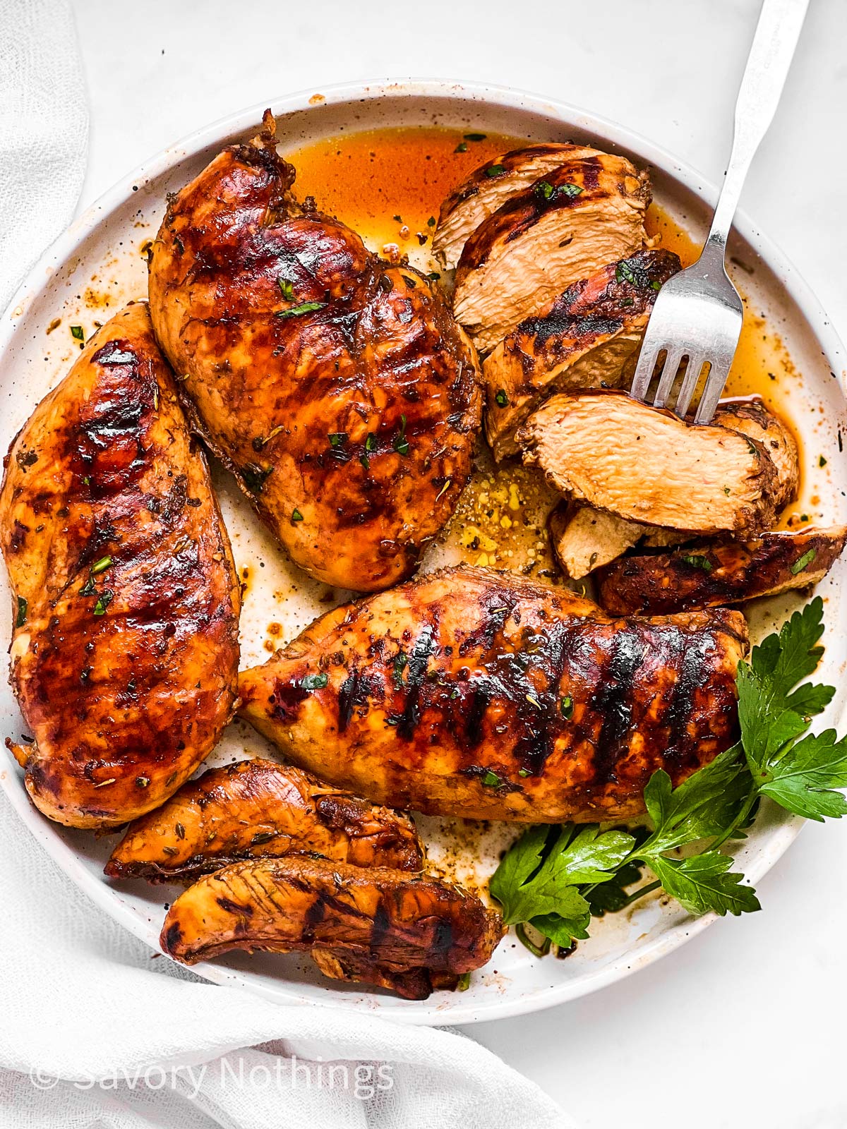 overhead view of grilled chicken breast in balsamic marinade on white plate