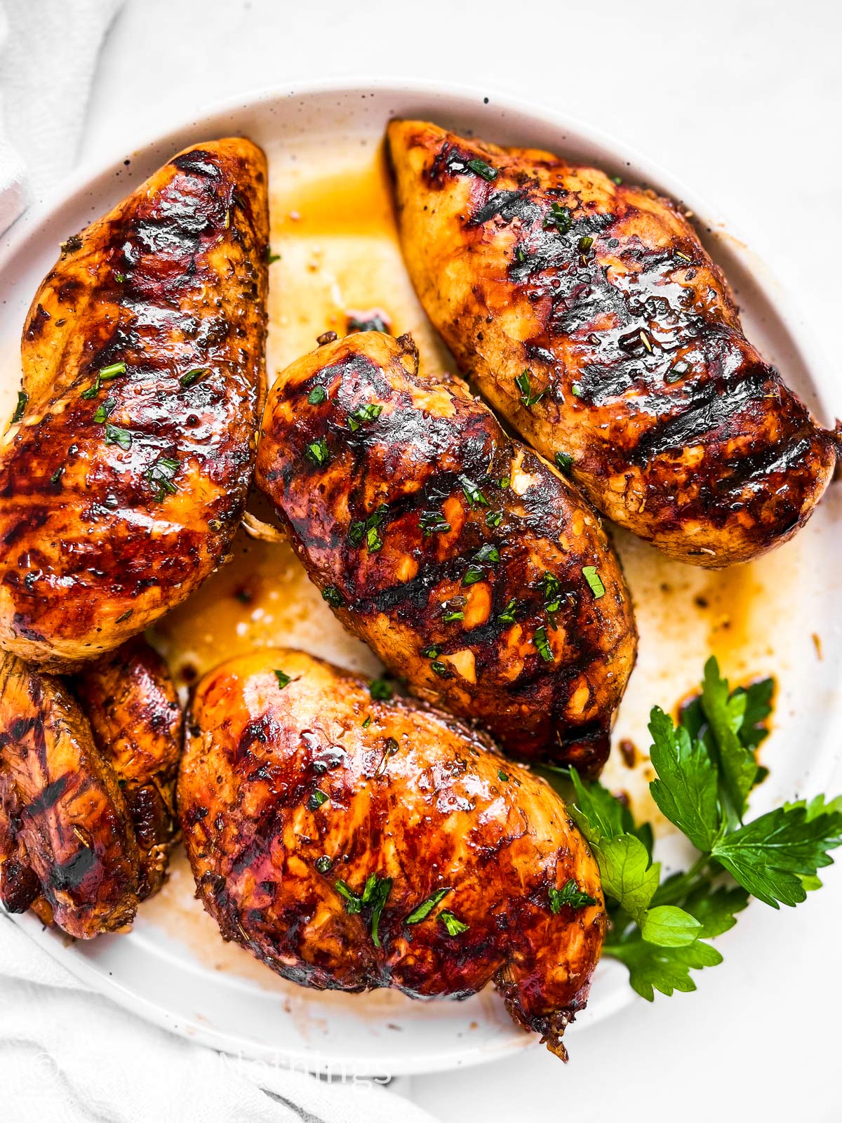 overhead view of grilled balsamic chicken breast on white plate