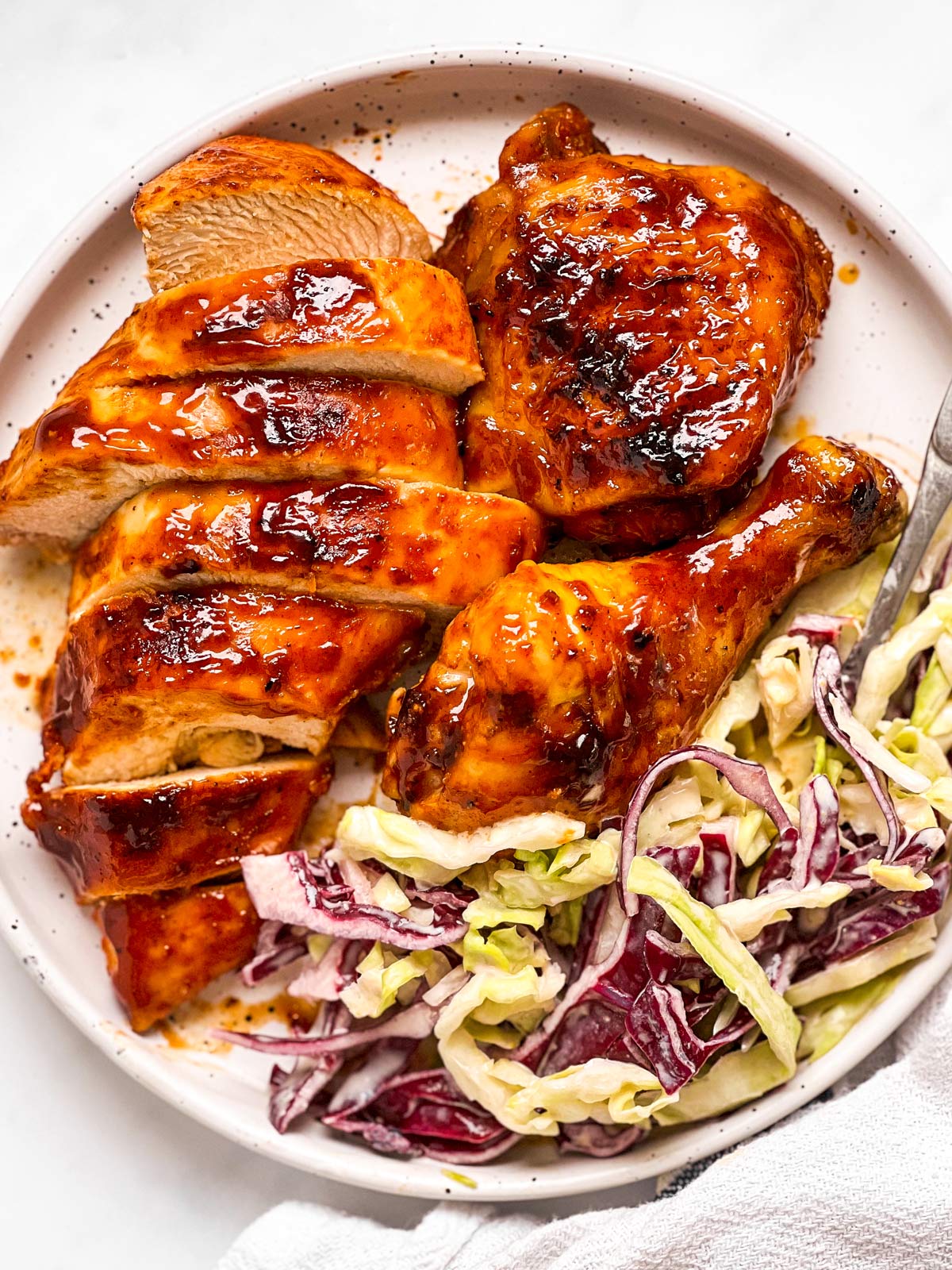 overhead view of sliced BBQ chicken and coleslaw on white plate