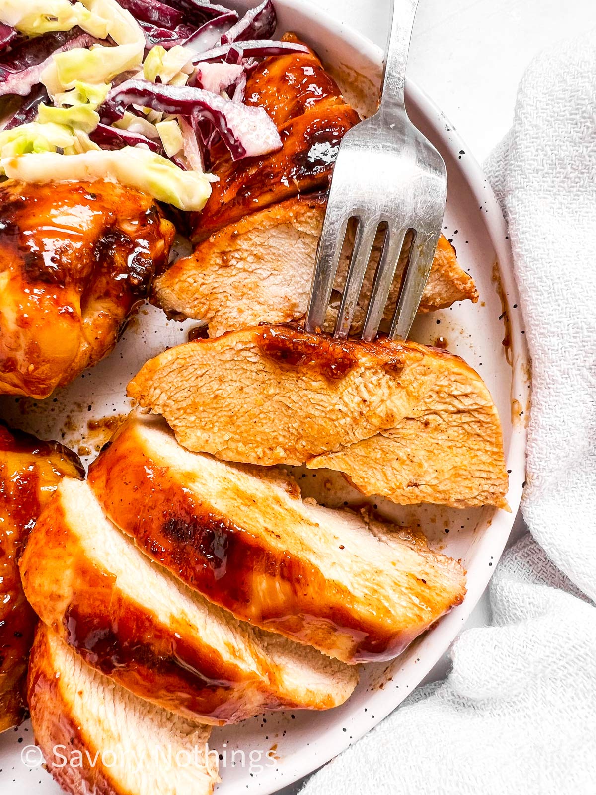 overhead closeup of sliced BBQ chicken breast with fork stuck into one piece