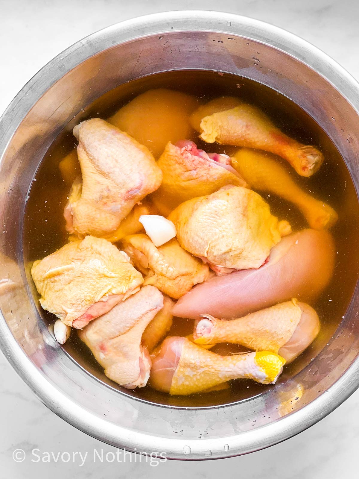 overhead view of raw chicken pieces in brine