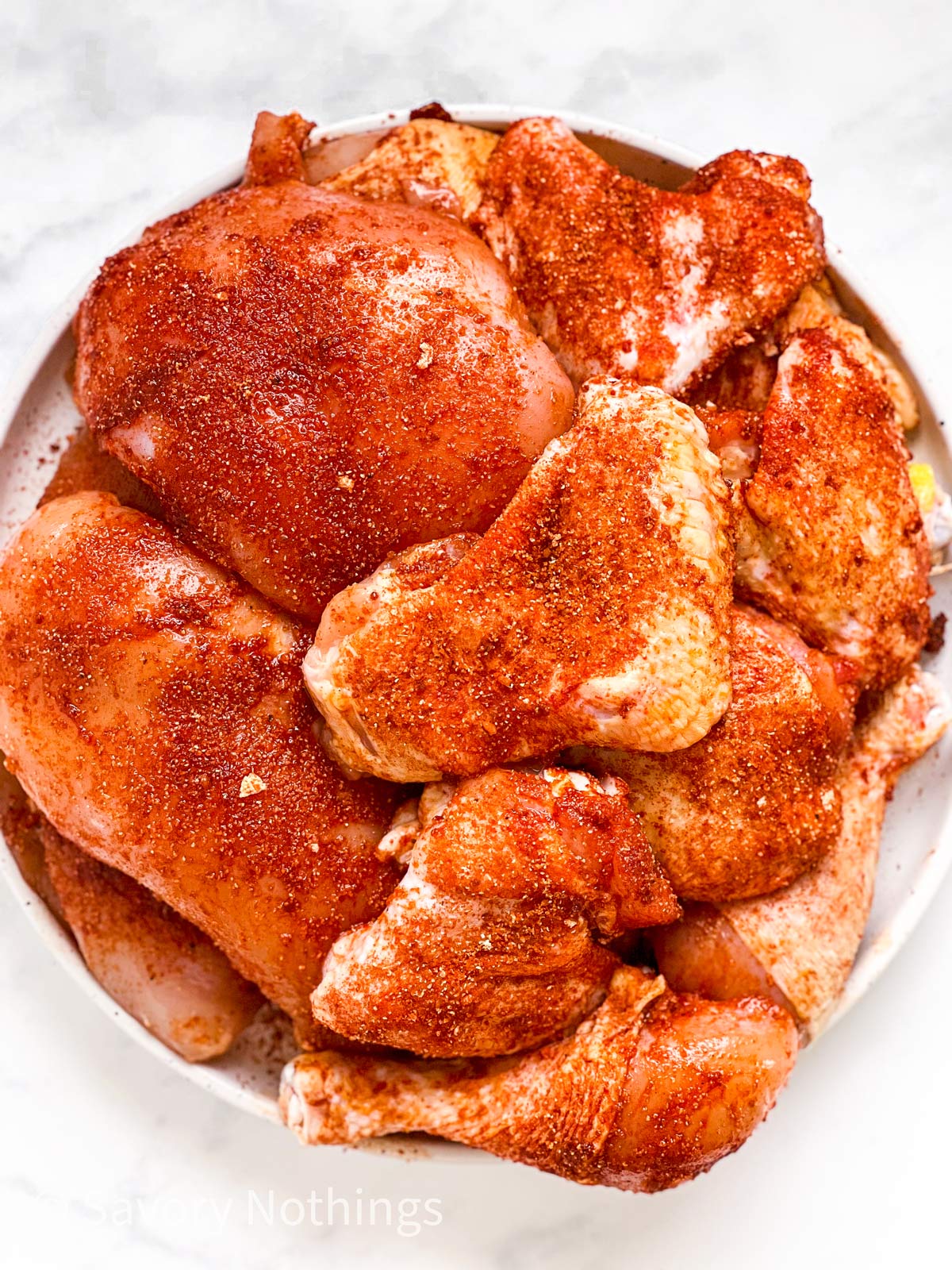 overhead view of seasoned chicken pieces on white plate