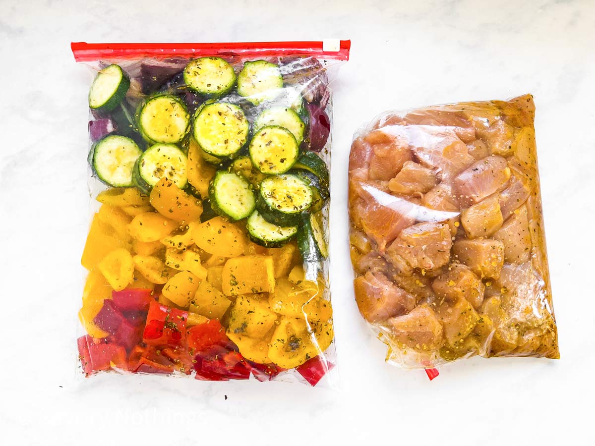 plastic bag filled with vegetables and plastic bag filled with chicken pieces on light stone surface