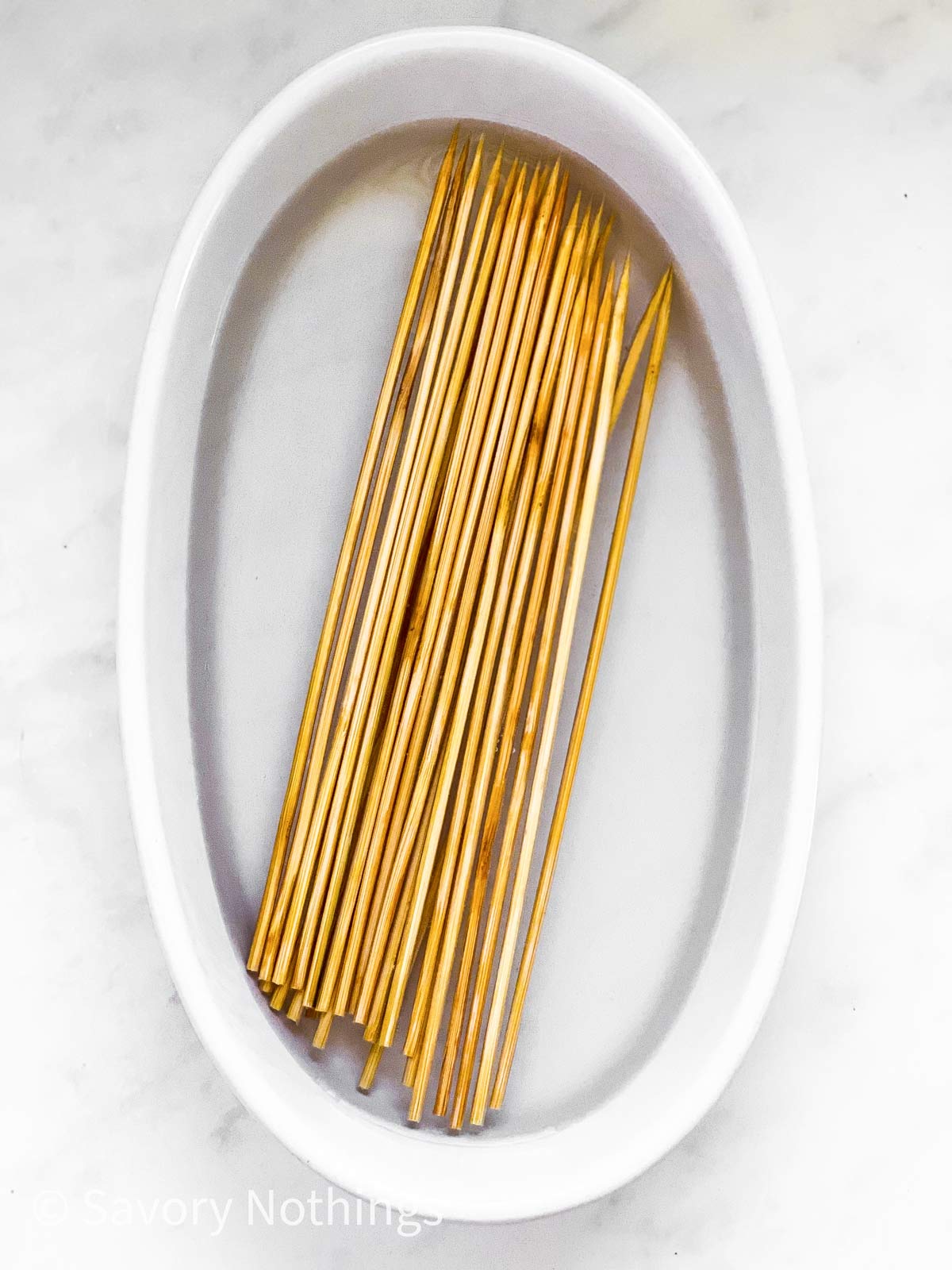 wooden skewers in an oval white dish in water