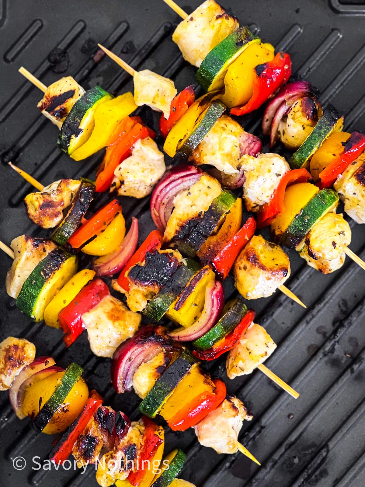 overhead view of chicken skewers on a grill plate
