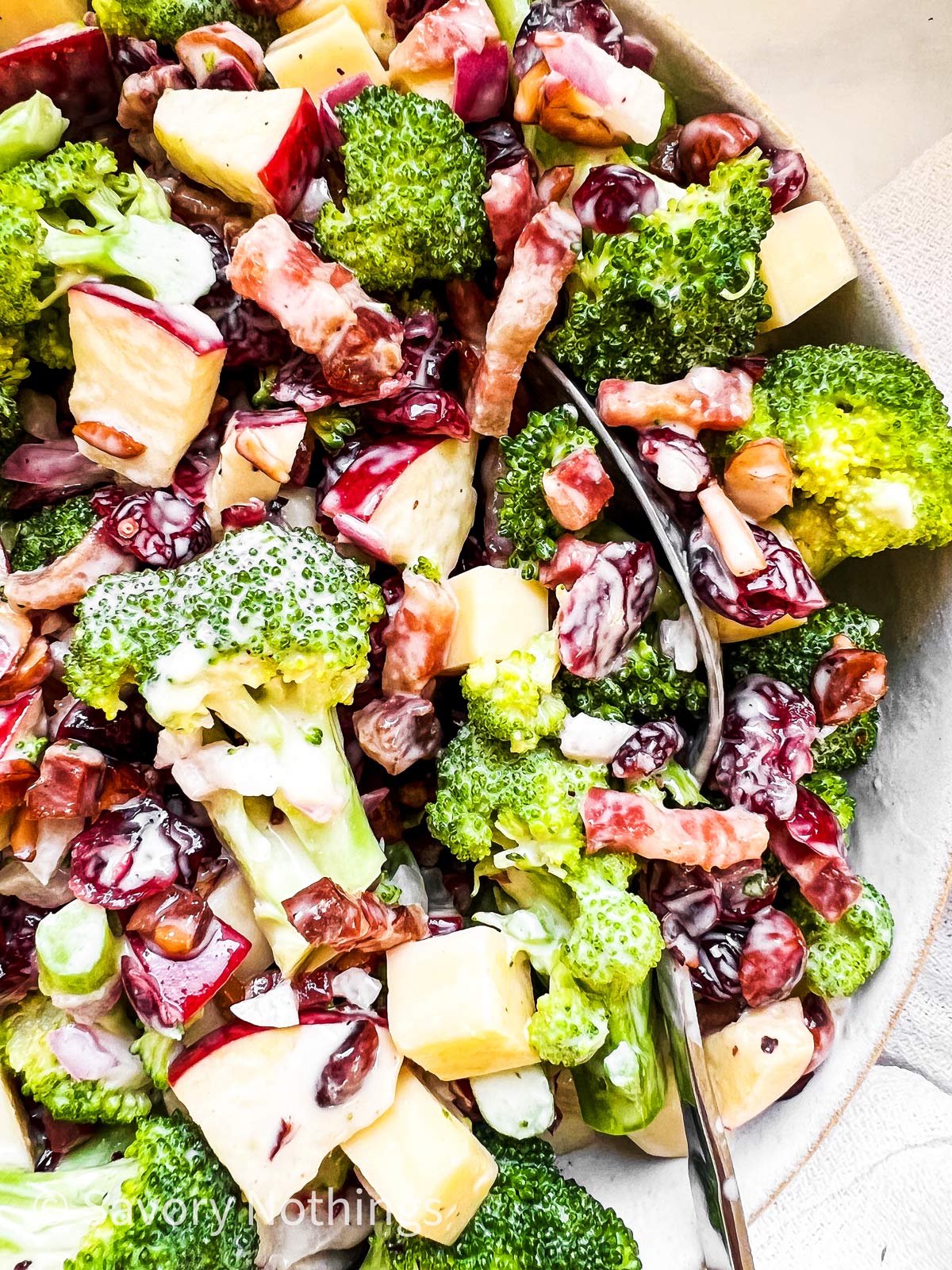 close up photo of spoon digging into a bowl of broccoli salad