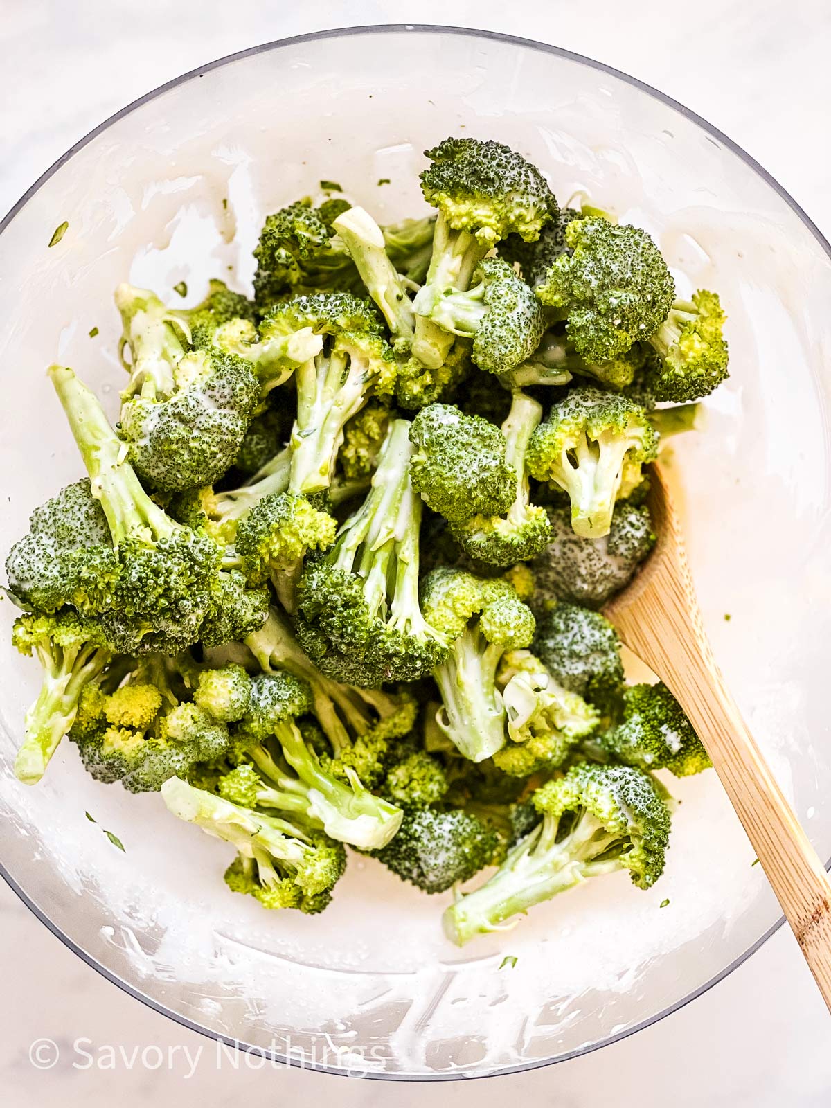 broccoli florets in glass bowl with creamy mayonnaise dressing