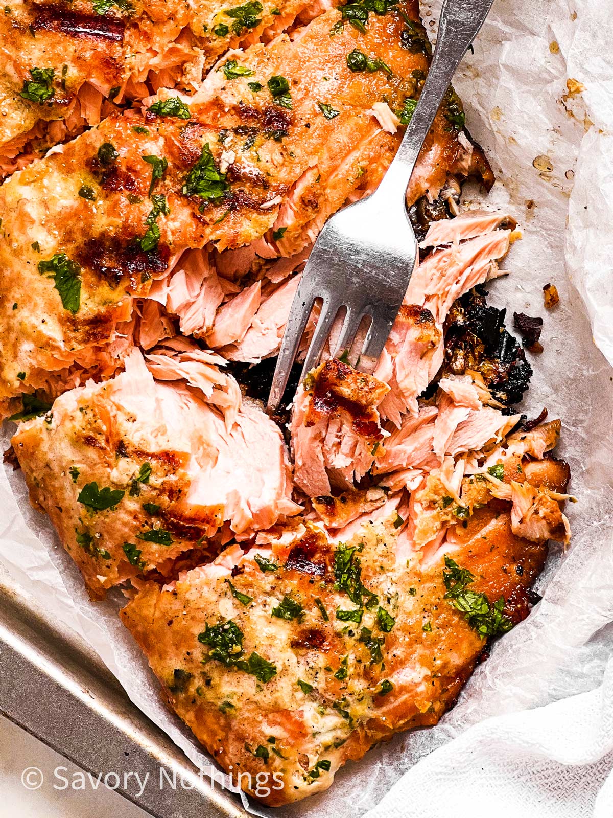 close up view of marinated and grilled salmon fillet with fork stuck in one piece