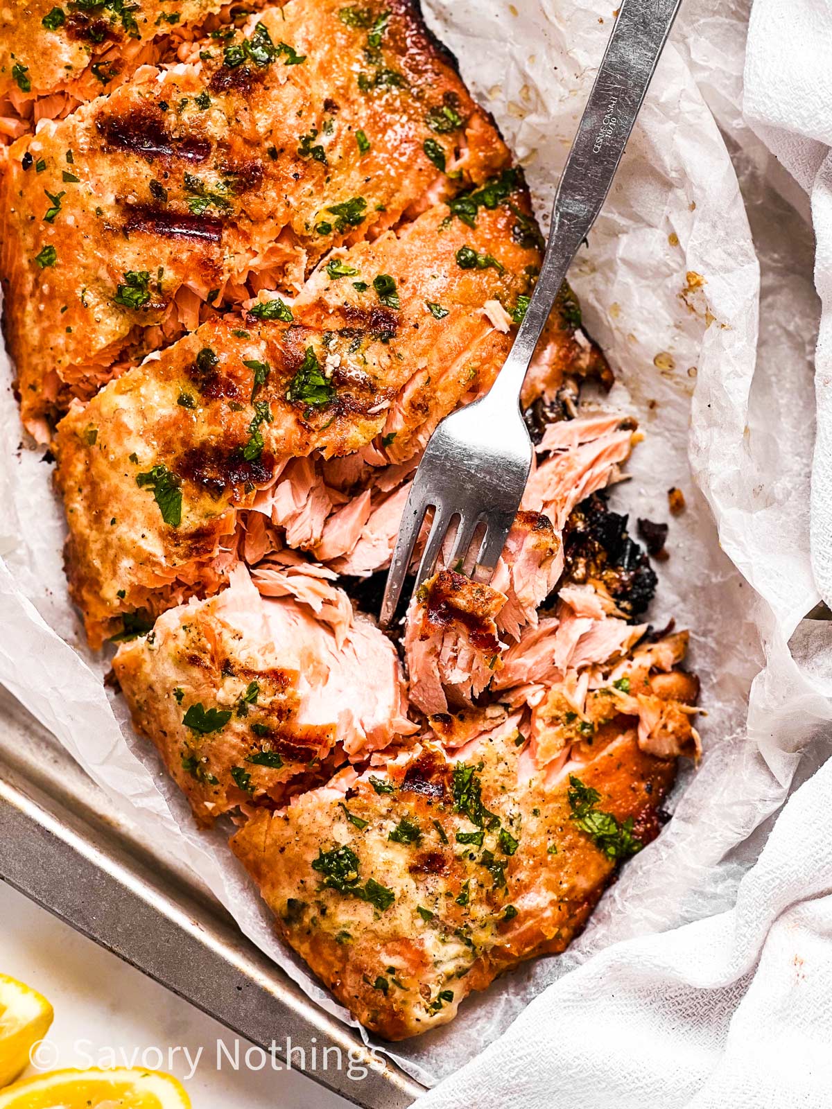 overhead view of marinated and grilled salmon fillet with fork stuck in one piece