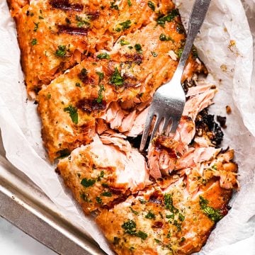 overhead close up view of marinated and grilled salmon fillet with fork stuck in one piece