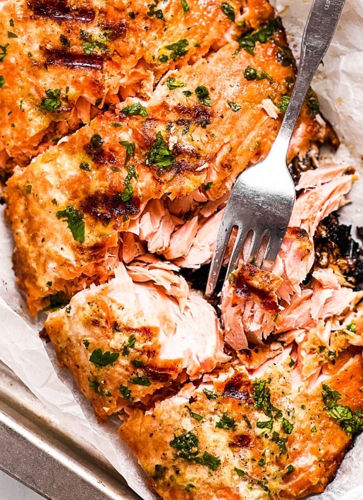 overhead close up view of marinated and grilled salmon fillet with fork stuck in one piece