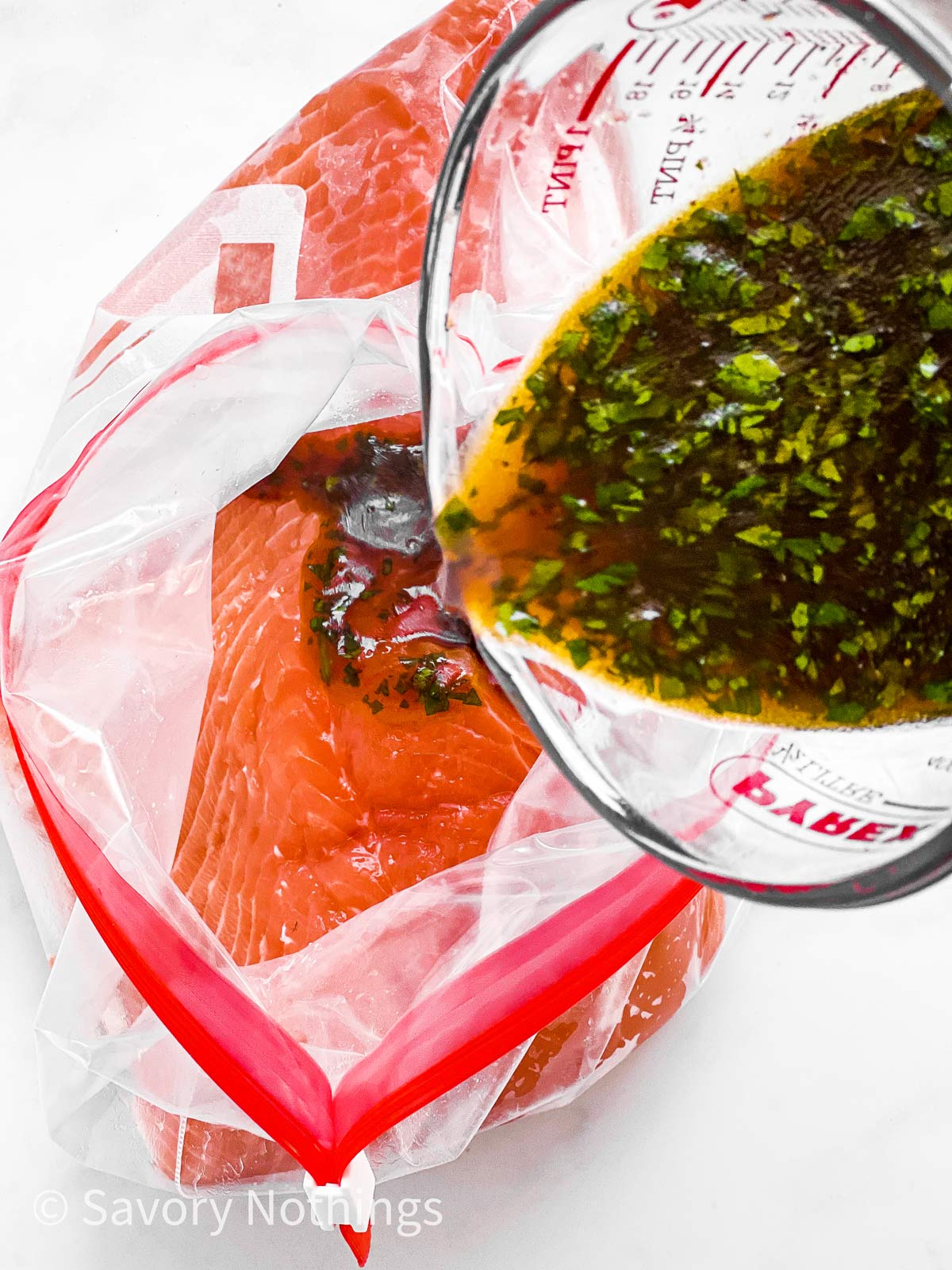 salmon marinade pouring over raw salmon fillet in zip-top bag