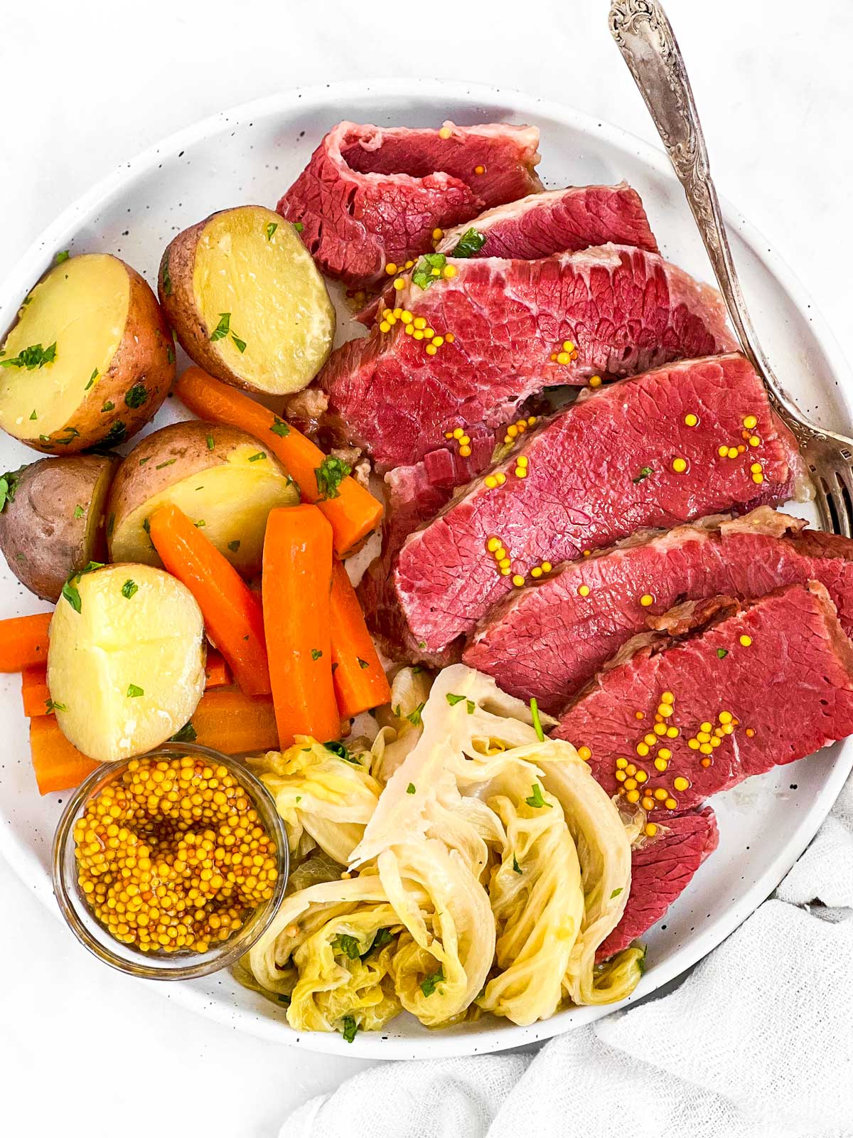 corned beef and boiled vegetables on plate with a fork