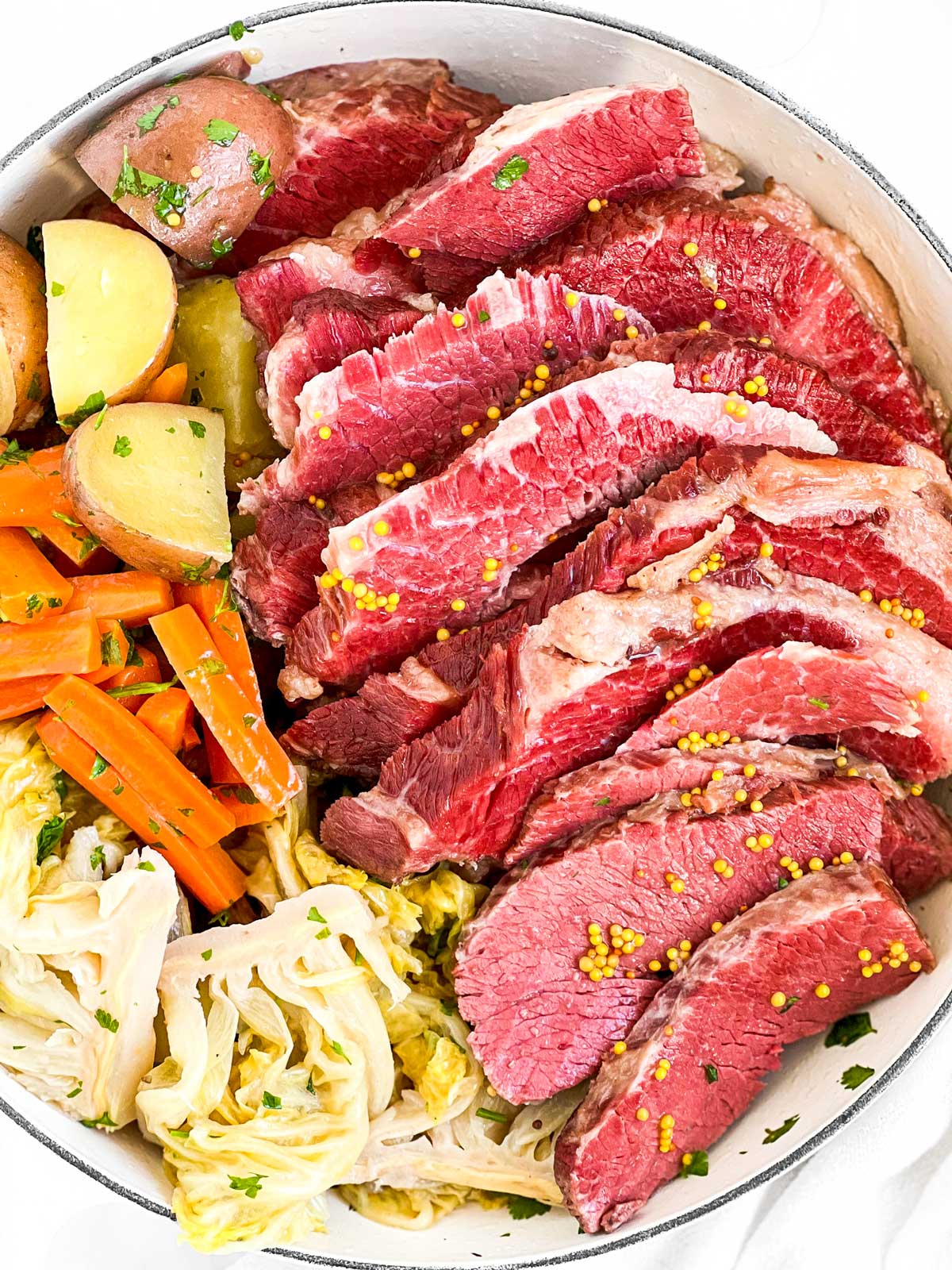 overhead view of sliced corned beef and vegetables in white round pot