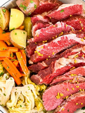 overhead view of sliced corned beef and vegetables in white round pot