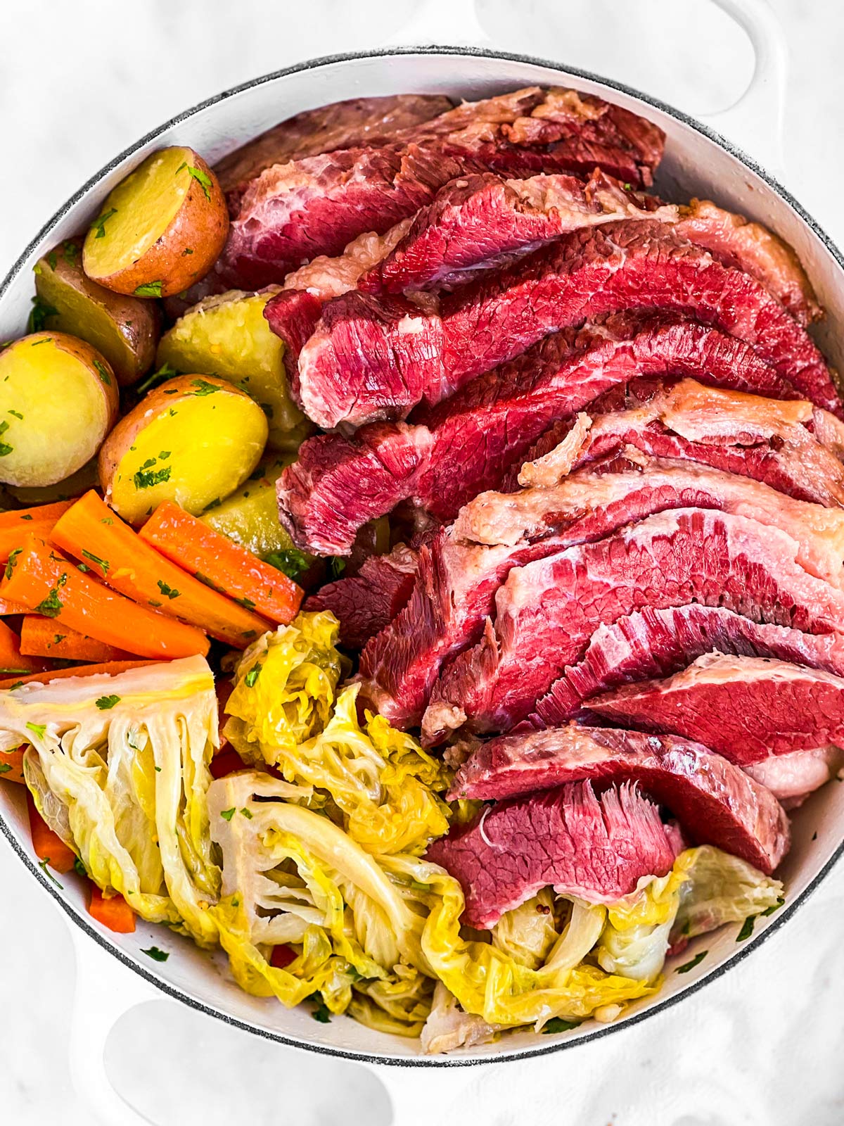 overhead view of sliced corned beef in pot with cooked cabbage, carrots and potatoes