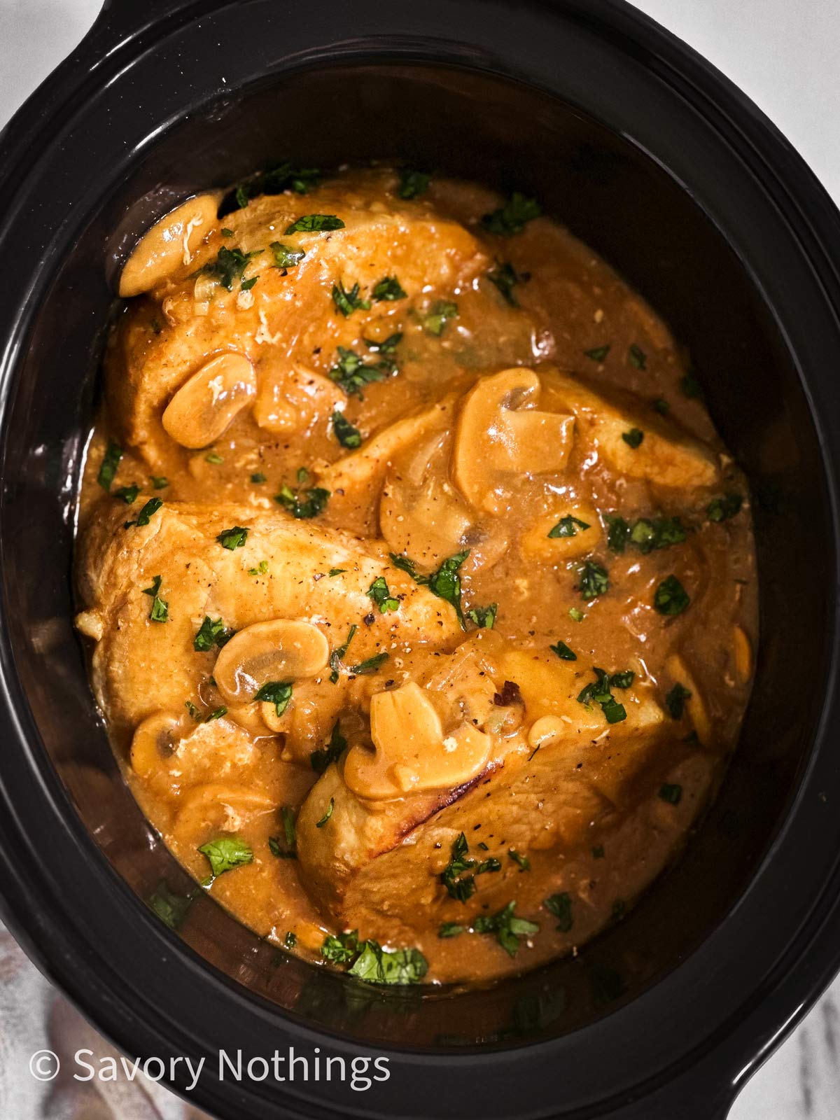 overhead view of pork chops and gravy in crock pot