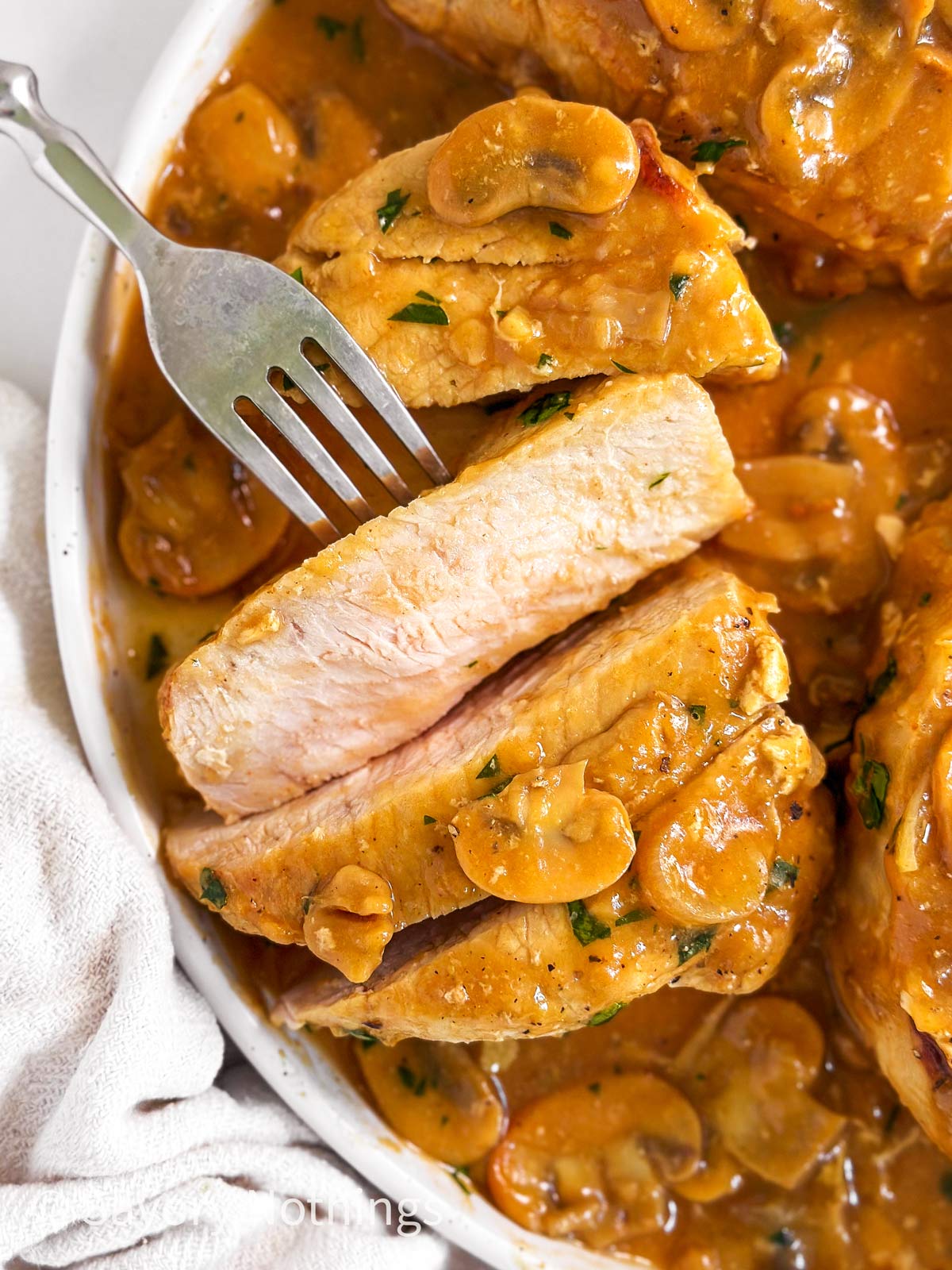 overhead view of sliced pork chop on white plate with mushroom gravy