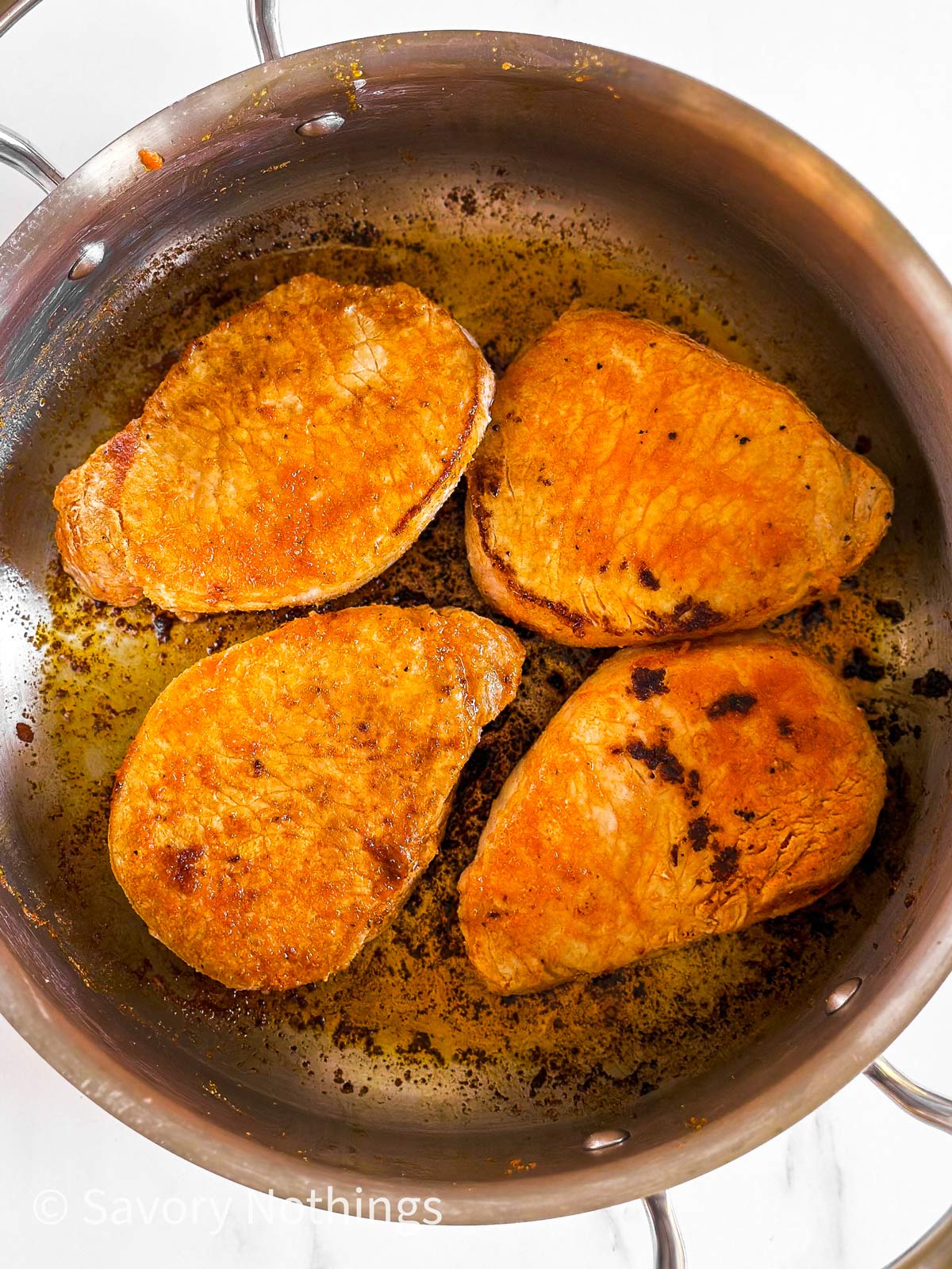 overhead view of 4 browned pork chops in skillet