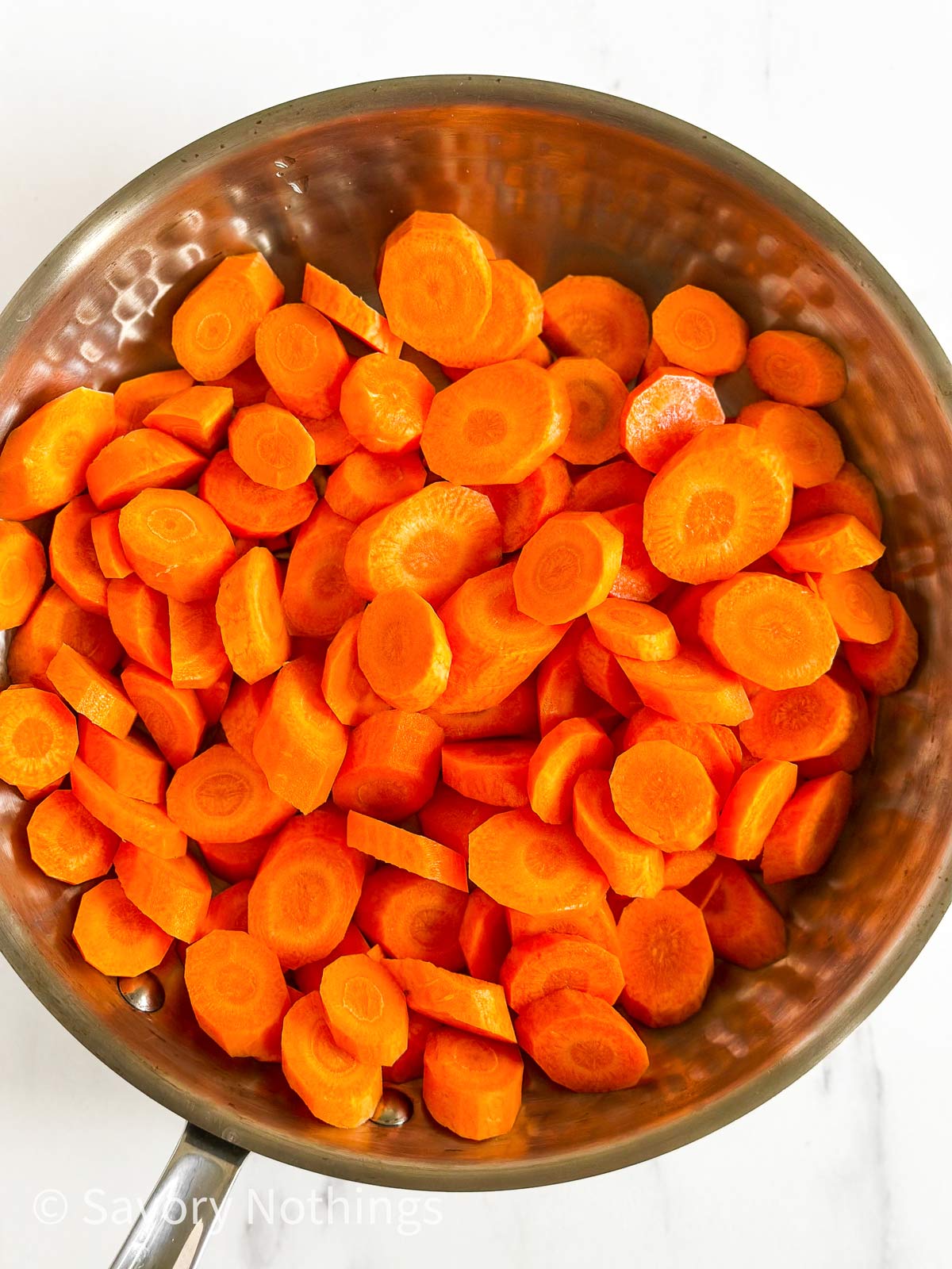 overhead view of raw sliced carrots in skillet