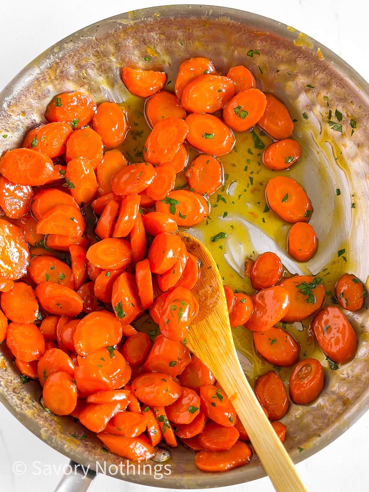 overhead view of glazed carrots in skillet sprinkled with chopped parsley