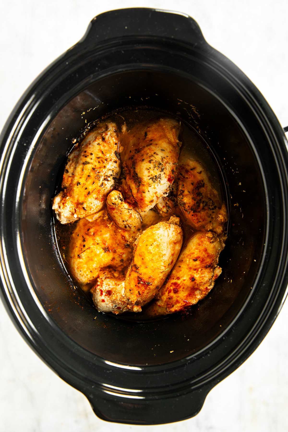 overhead view of cooked chicken breast in slow cooker crock