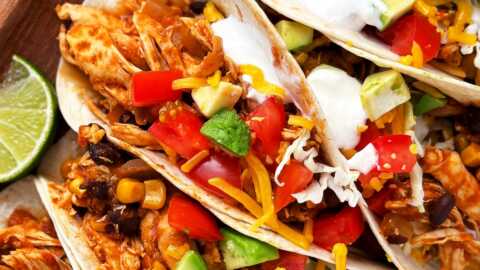 overhead close up view of crock pot chicken tacos with toppings on wooden platter