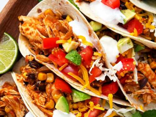 overhead close up view of crock pot chicken tacos with toppings on wooden platter