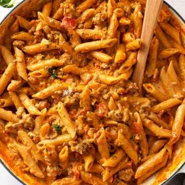 overhead view of white skillet filled with Italian sausage and peppers pasta