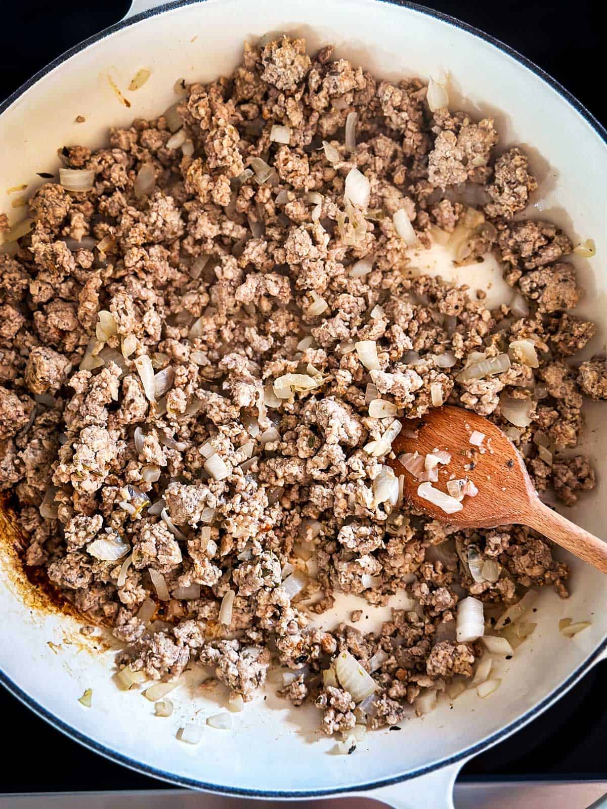 overhead view of cooked Italian sausage and onion in skillet