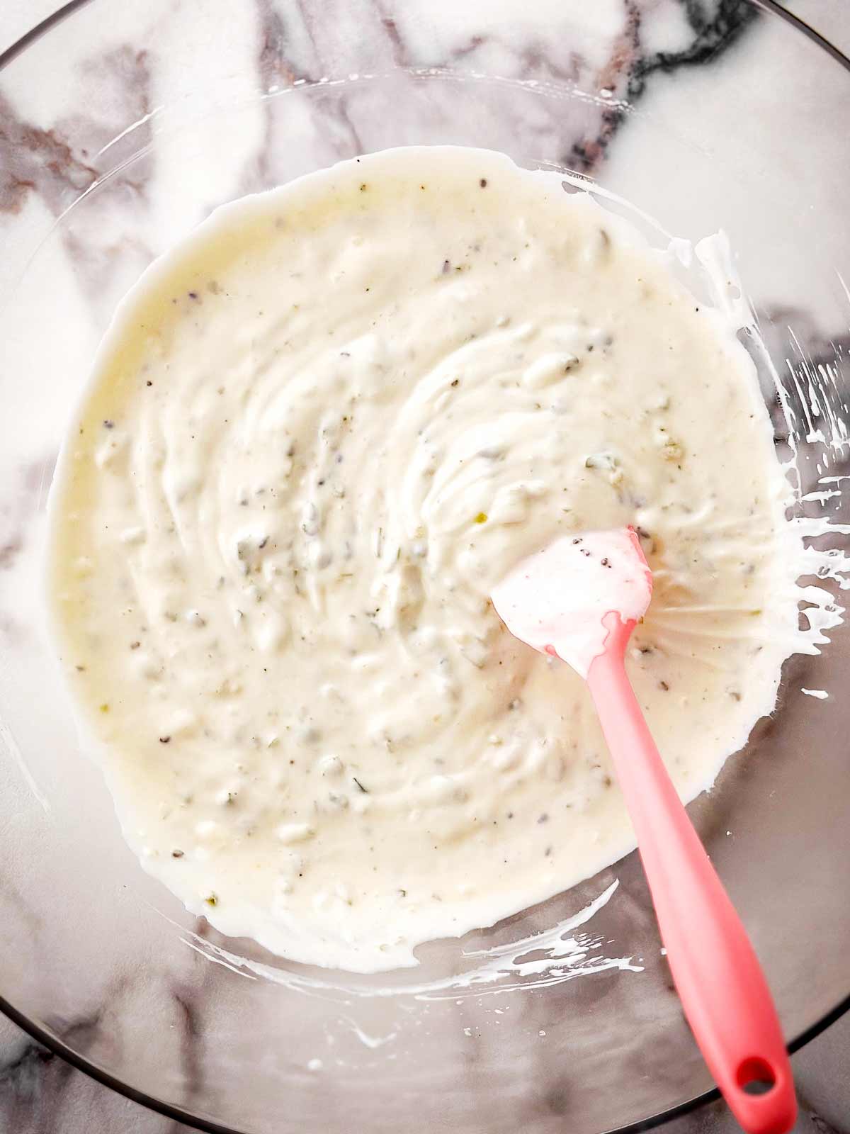 overhead view of mayonnaise dressing in clear glass bowl