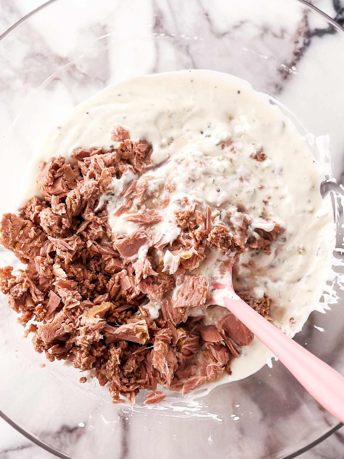 overhead view of canned tuna in mayonnaise dressing in a clear glass bowl