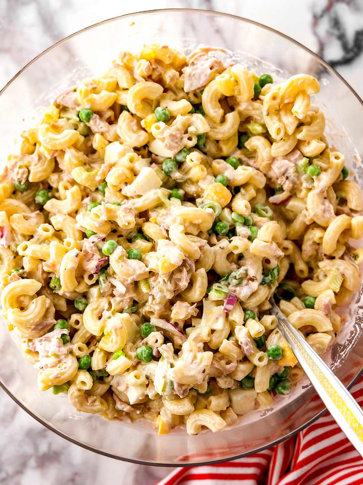 overhead view of mixed tuna macaroni salad in clear glass bowl