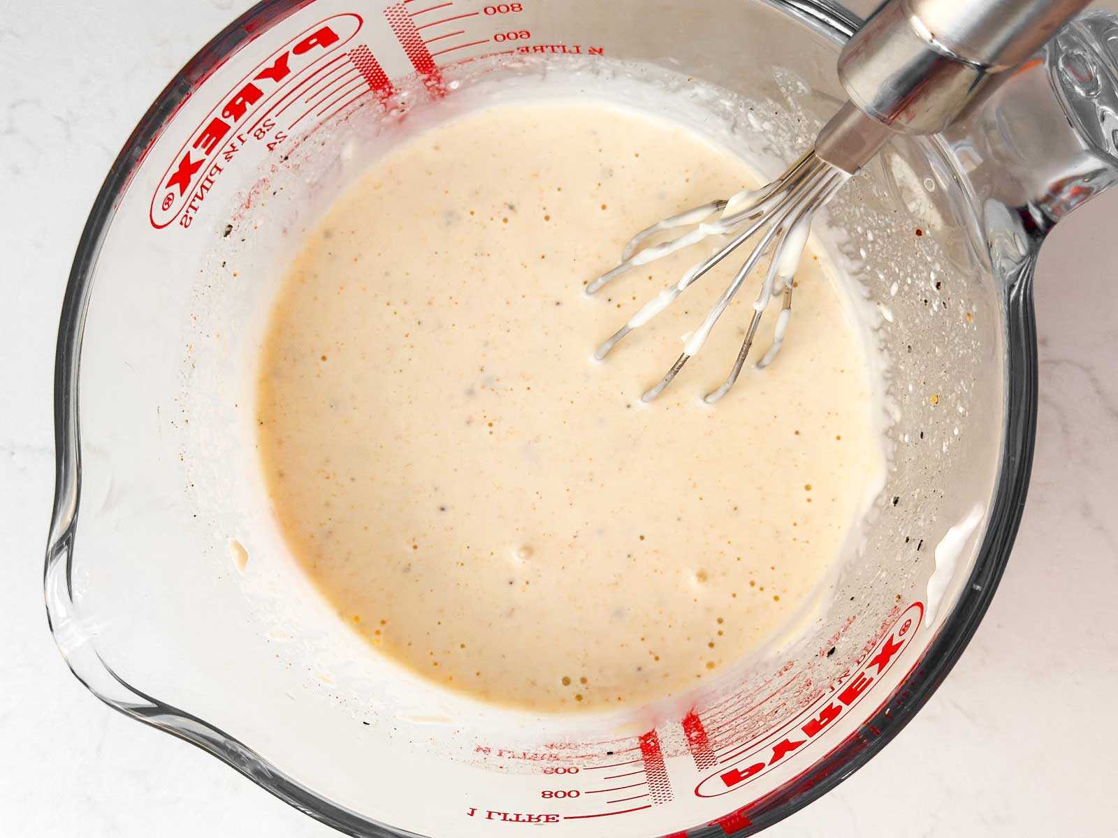 overhead view of coleslaw dressing in glass measuring cup